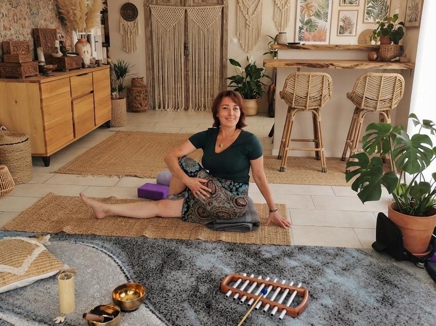 Oksana en posture de yoga dans un studio naturel et lumineux avec instruments de sonothérapie